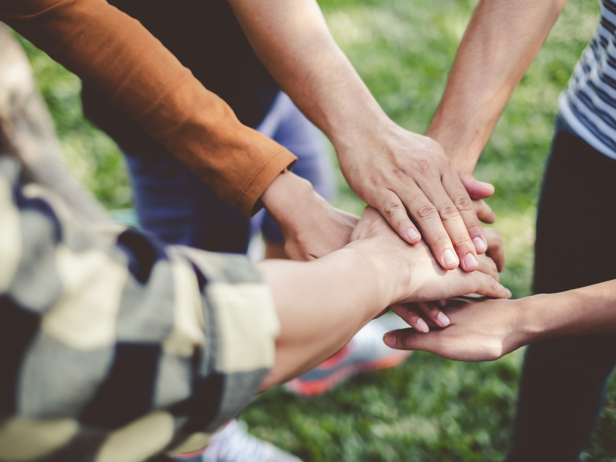 Teens standing in a circle with their hands in the middle.