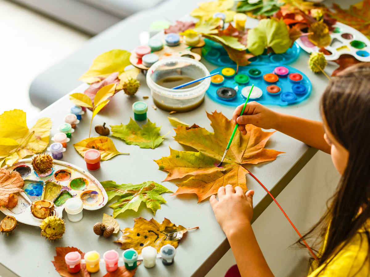 A child painting on an autumn leaf.