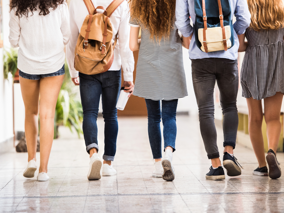 Teens walking away from the camera in a school hallway.